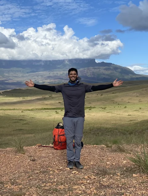Carlos Polly standing in front of a mountain landscape.