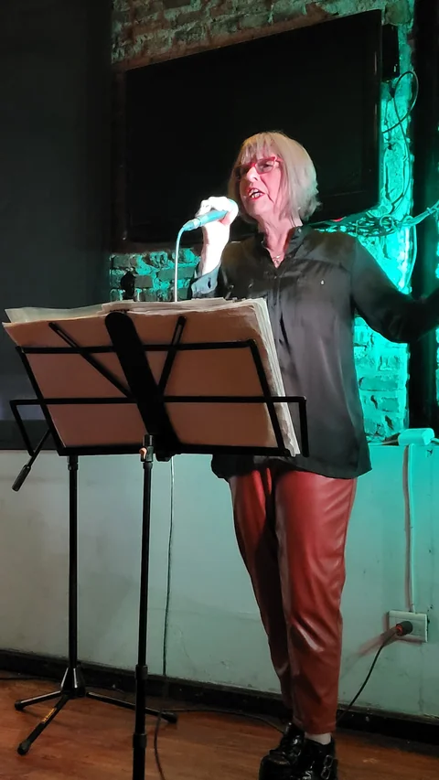 Marce Arias singing into a microphone during a live performance.